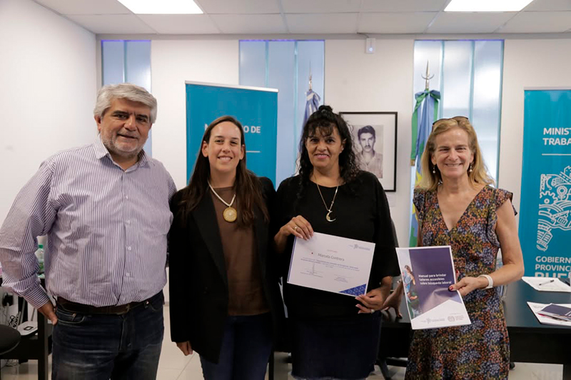 Walter Correa, Brenda Pignol Ramos, una trabajadora de PBA con su diploma y María Eugenia Quintana con el manual en la mano.